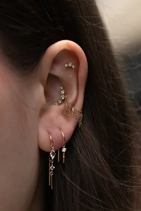 Ohr mit mehreren Lobe Piercings, Chains und hängendem Schmuck