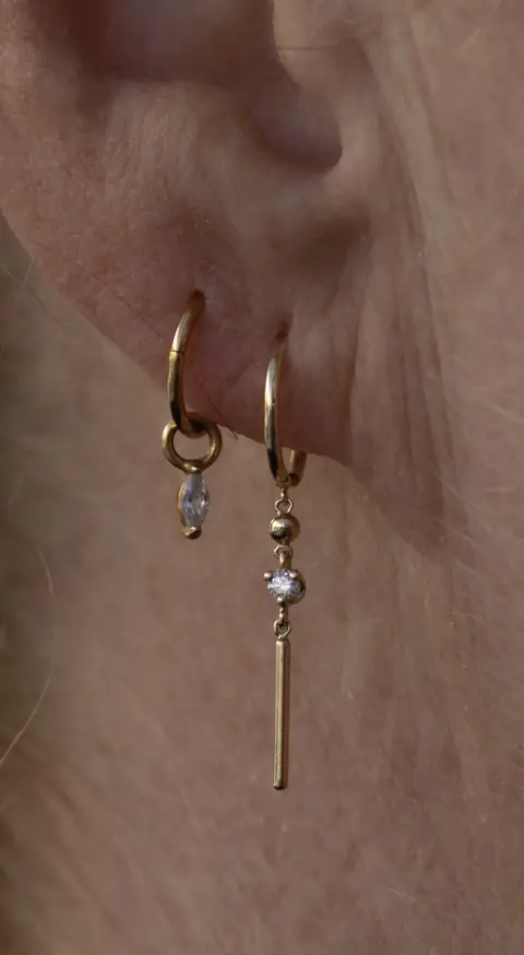 Zwei Ohrläppchen-Piercings mit goldenen Threader-Anhängern