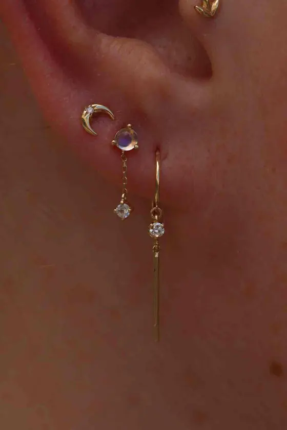 Ohr mit mehreren Piercings und feinen goldenen Anhängern